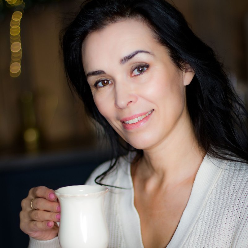 A woman smiling over a cup of tea